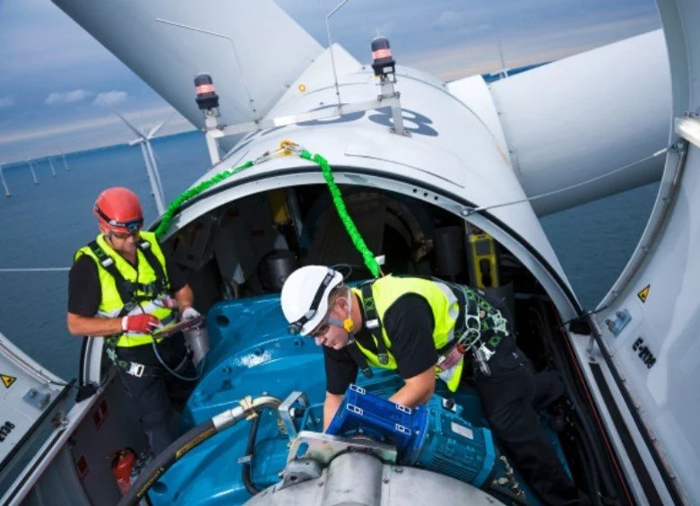 Two technicians working on mechanical equipment inside a wind turbine